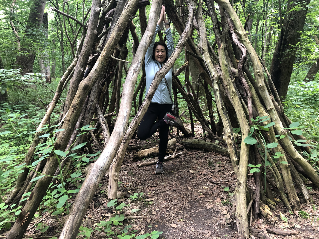 Motoko in tree pose framed by a natural archway of branches in the woods