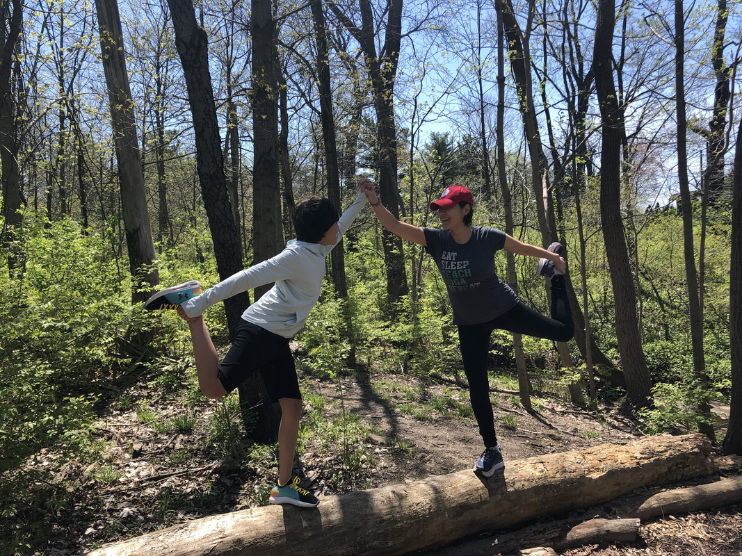 Motoko and a young student balancing together in dancer&rsquo;s pose on a fallen log